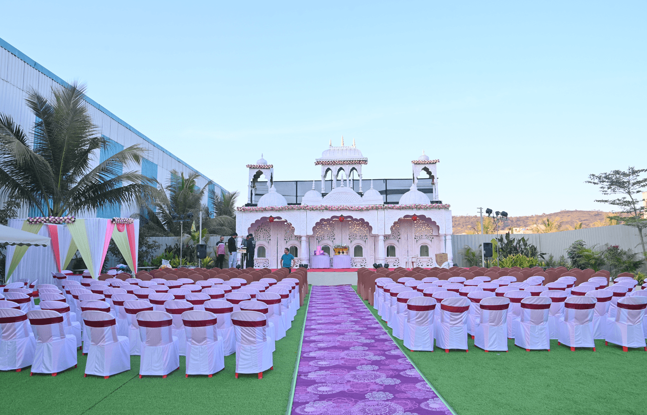 Lawn ceremony set-up on artificial turf with a violet aisle runner, chairs in peacock sashes and the mandap at the head